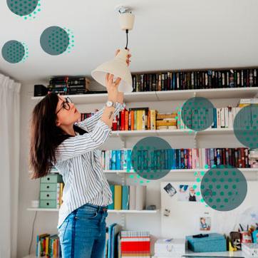 Woman fixing a light bulb on a ceiling lamp