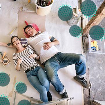 Couple lying on the floor covered with paper, surrounded by painting materials